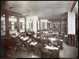 Muži a jedna žena pracují u stolů v kanceláři Metropolitan Life Insurance Co. na 23. ulici a Madison Avenue, New York, 1907 (stříbrný želatinový tisk)